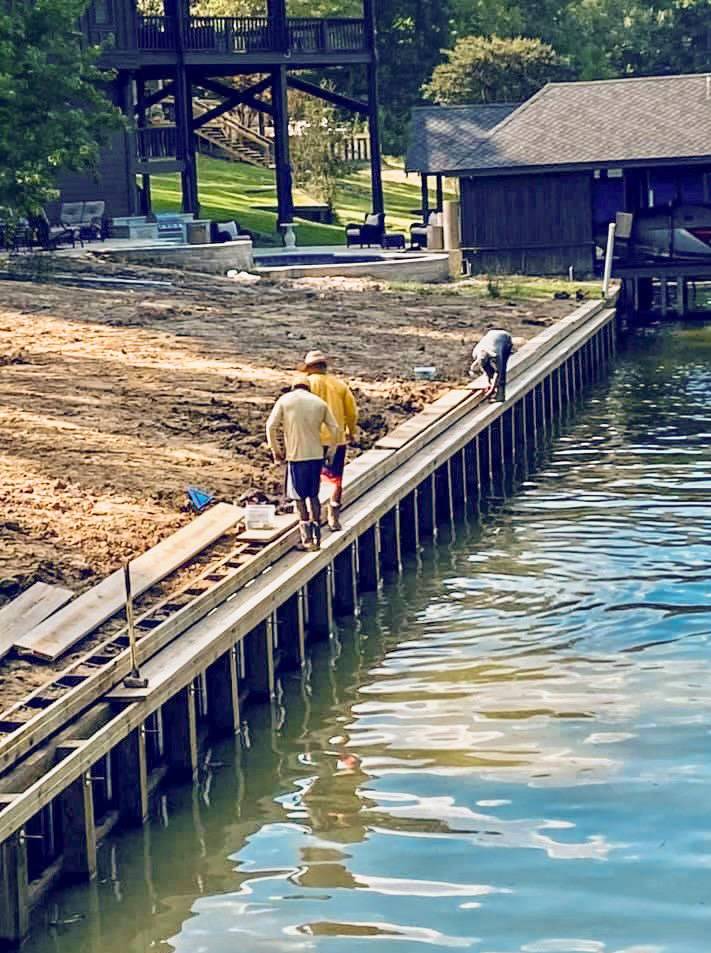 Two people walking on a dock next to water.